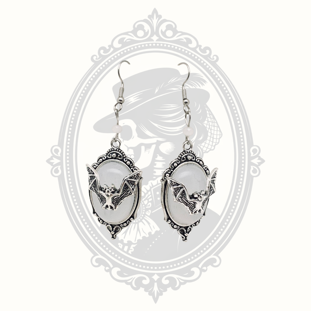 White faceted gemstone Gothic bat drop earrings with ornate silver-tone frames.