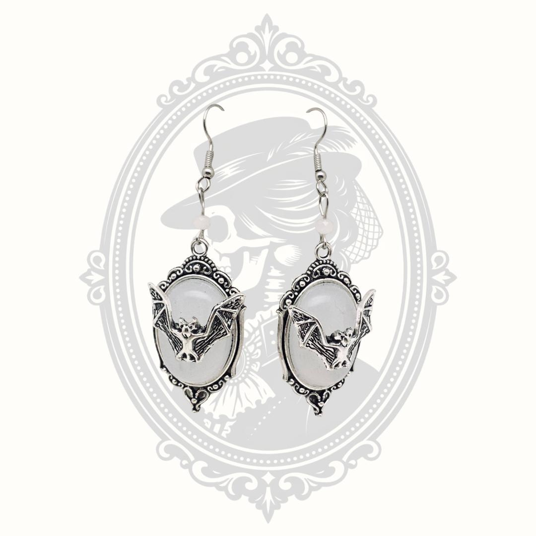 White faceted gemstone Gothic bat drop earrings with ornate silver-tone frames.