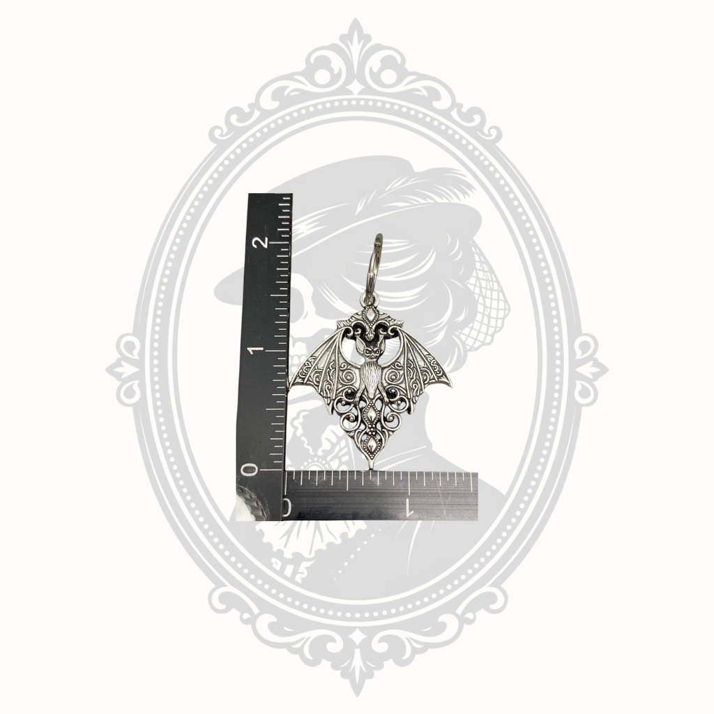 Gothic bat huggie earring shown beside a ruler for size reference.