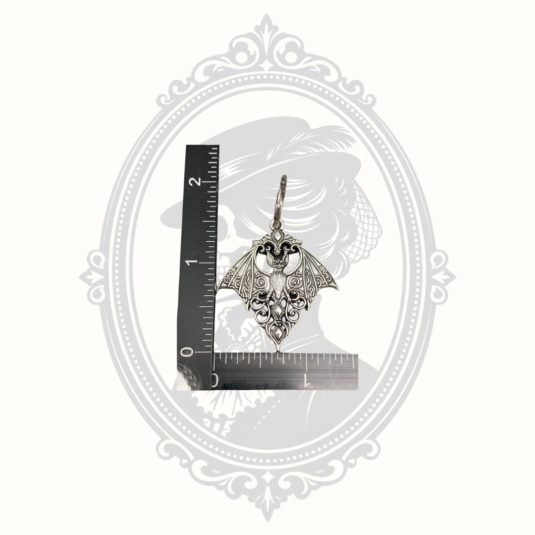 Gothic bat huggie earring shown beside a ruler for size reference.
