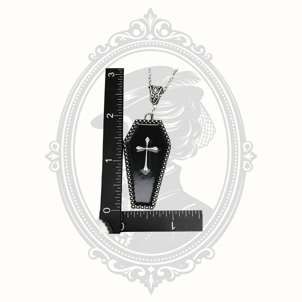 Gothic coffin cross pendant necklace shown beside ruler for size reference.