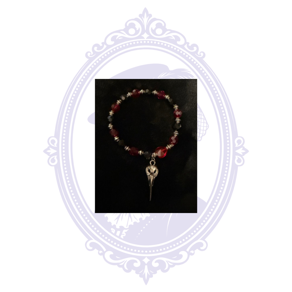 Gothic red and dark metallic beaded bracelet with dangling plague doctor-style bird skull charm.