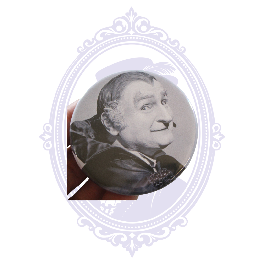 Hand holding Grandpa Munster 2.25-inch metal-backed pin button showing its size