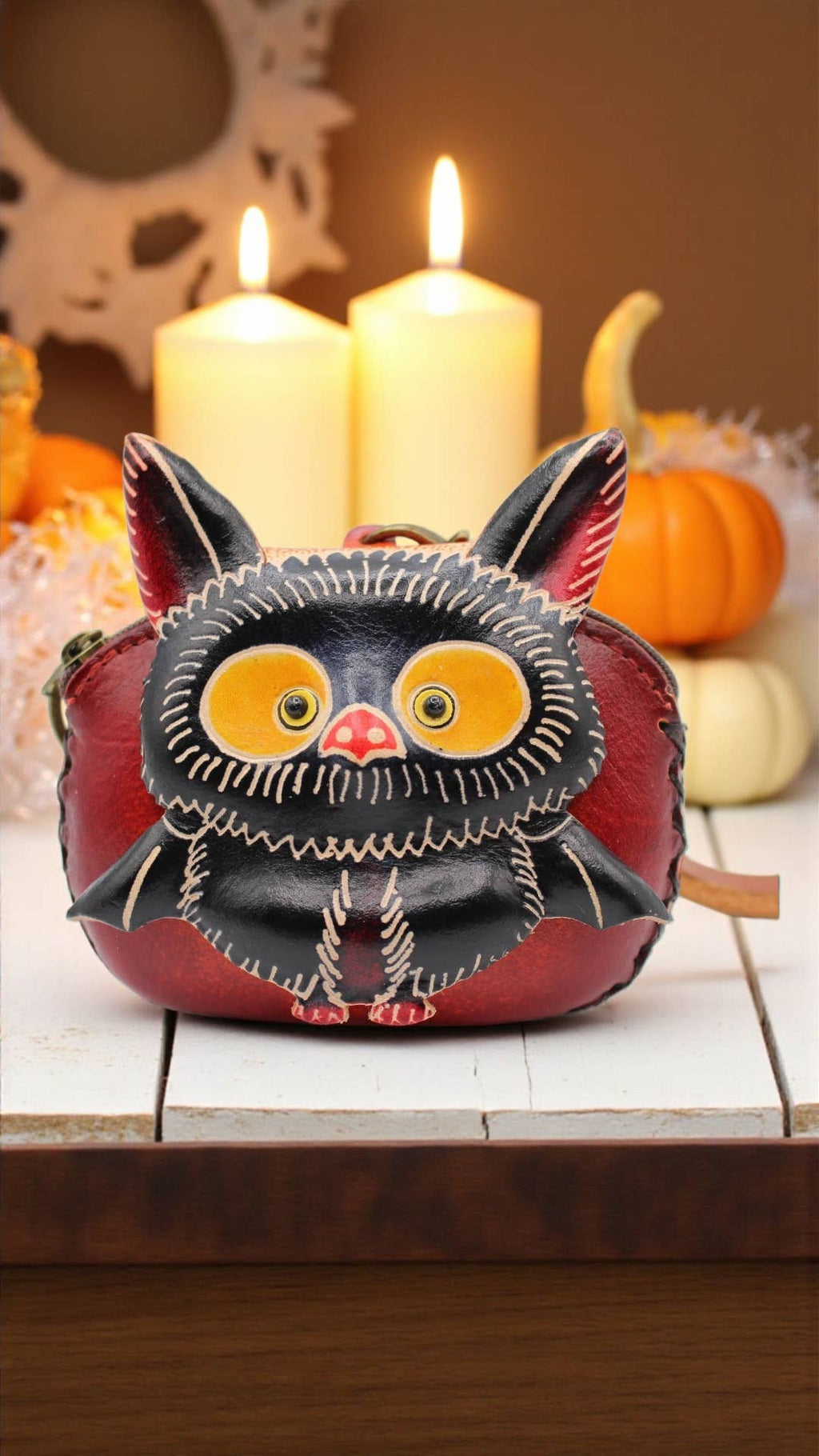 Handmade leather baby bat coin purse wristlet displayed with pumpkins and candles