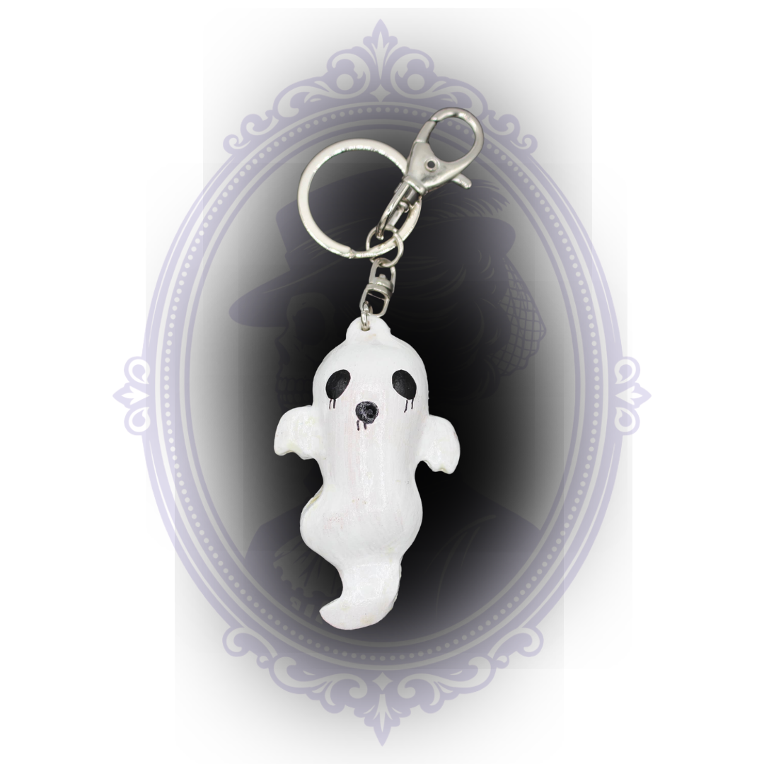 White handmade ghost keychain with curved ghost shape, black painted face, and silver-tone clip and keyring.