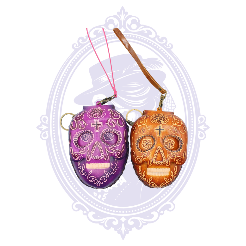 Purple and brown leather sugar skull coin purses shown together with wrist straps and key rings.