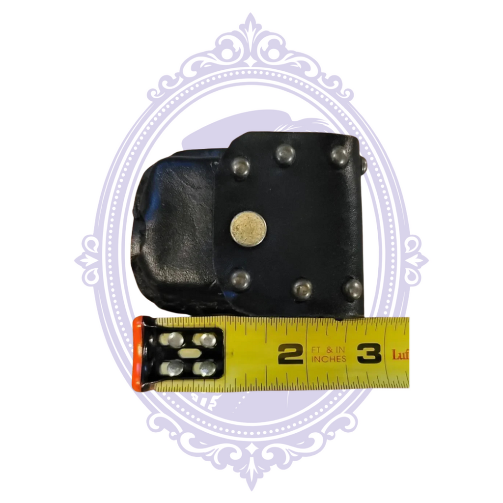 Angled black leather studded mini pouch with measuring tape showing compact size