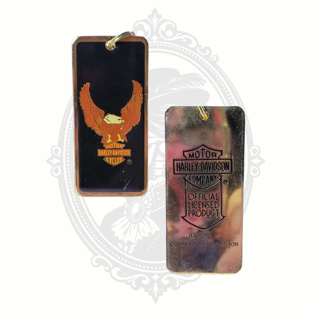 Two Harley-Davidson branded keychains on a decorative white background