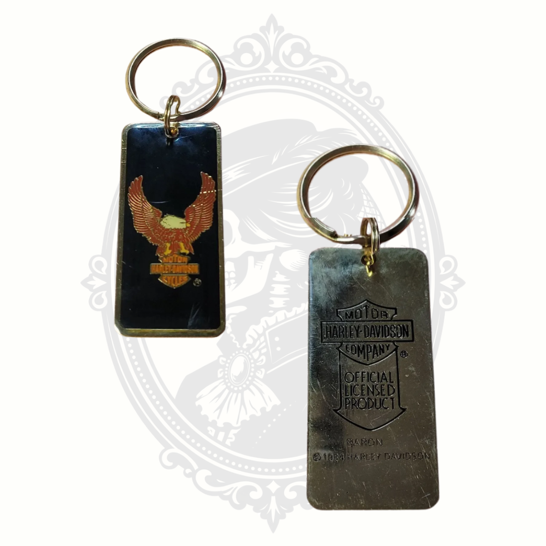 Two Harley Davidson keychains on a decorative white background