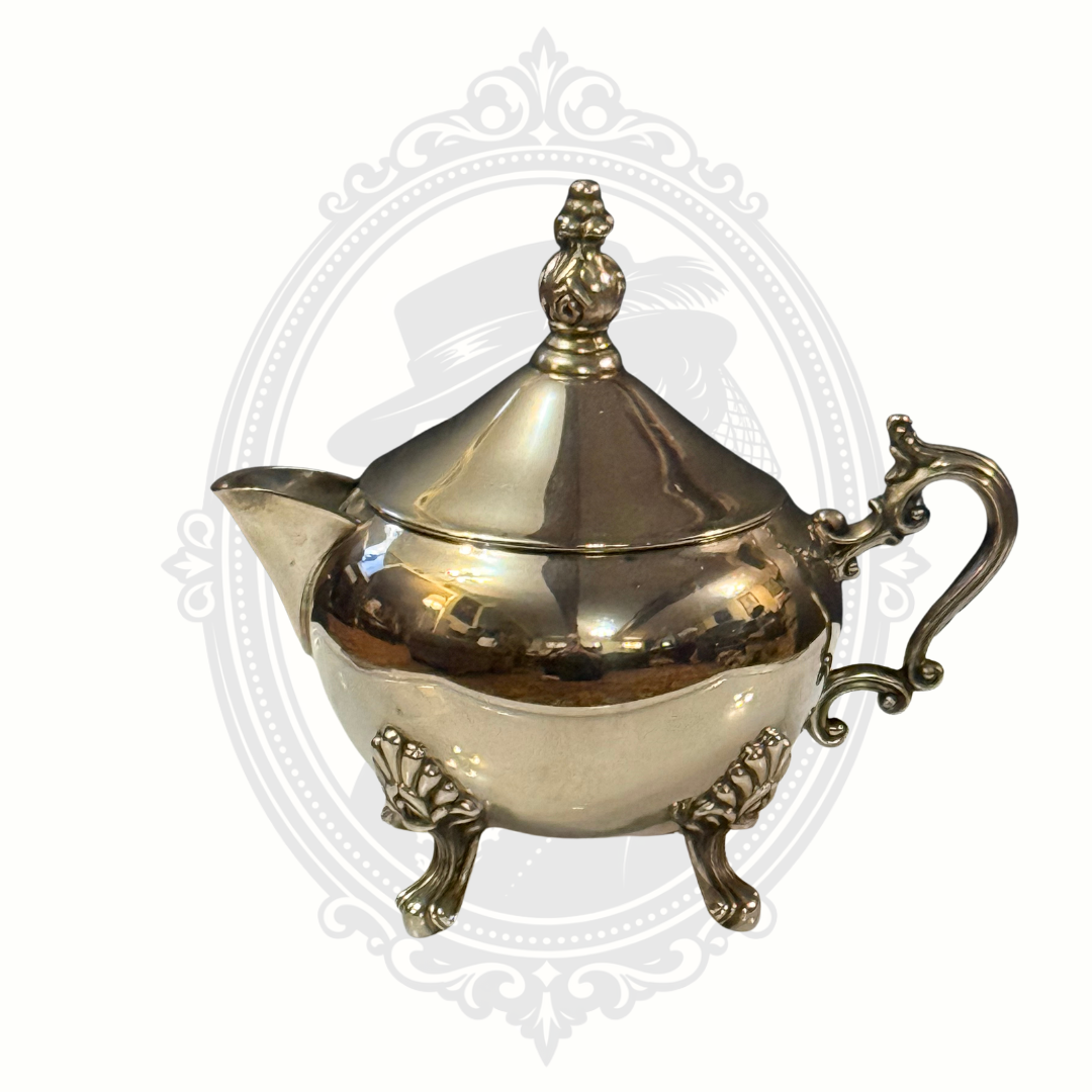 Decorative silver-plated teapot with intricate designs on a white background