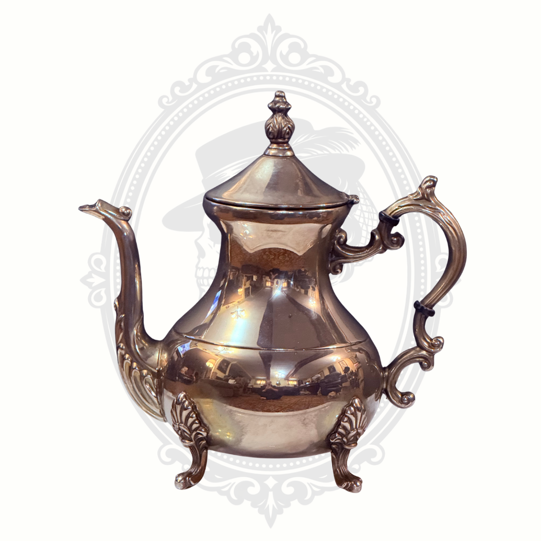Silver teapot with intricate designs on a white background