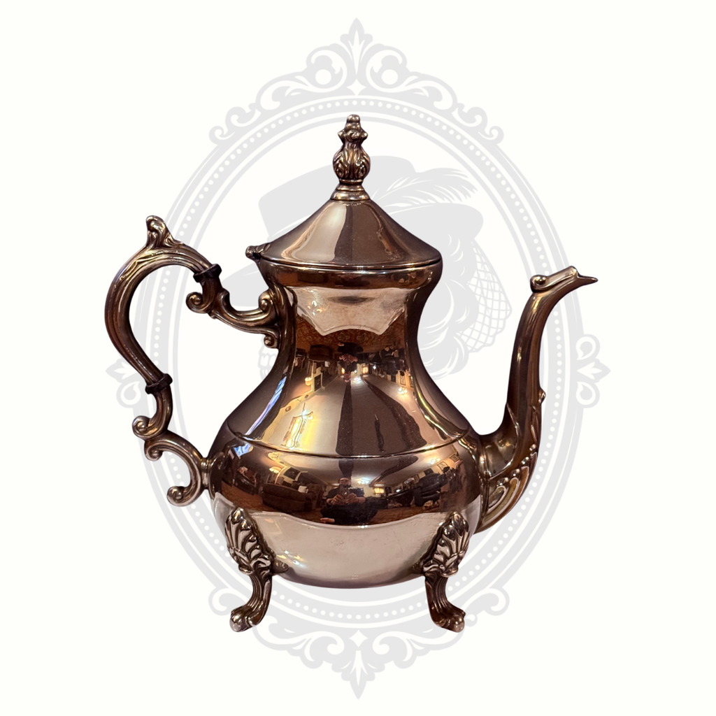 Silver-plated teapot with intricate designs on a white background