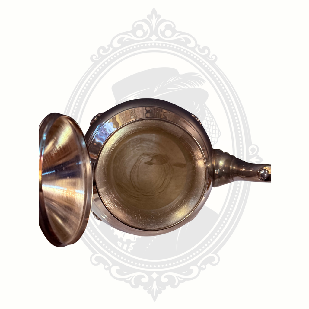 Interior view of silver-plated teapot on a decorative white background