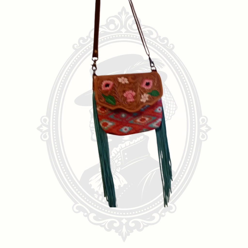 Myra Bag crossbody featuring tooled leather with floral detailing, colorful woven textile body, and long fringe accents.