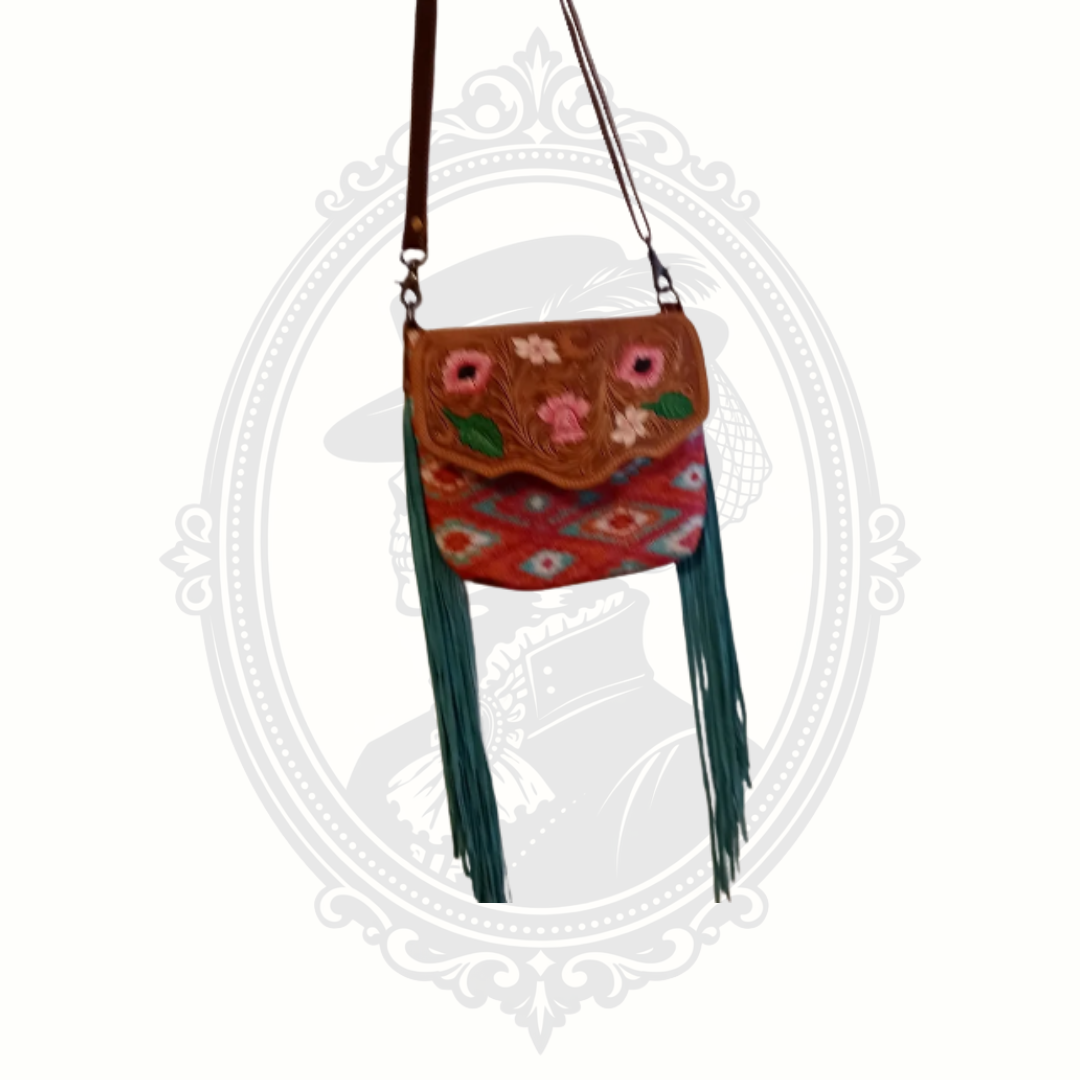 Myra Bag crossbody featuring tooled leather with floral detailing, colorful woven textile body, and long fringe accents.