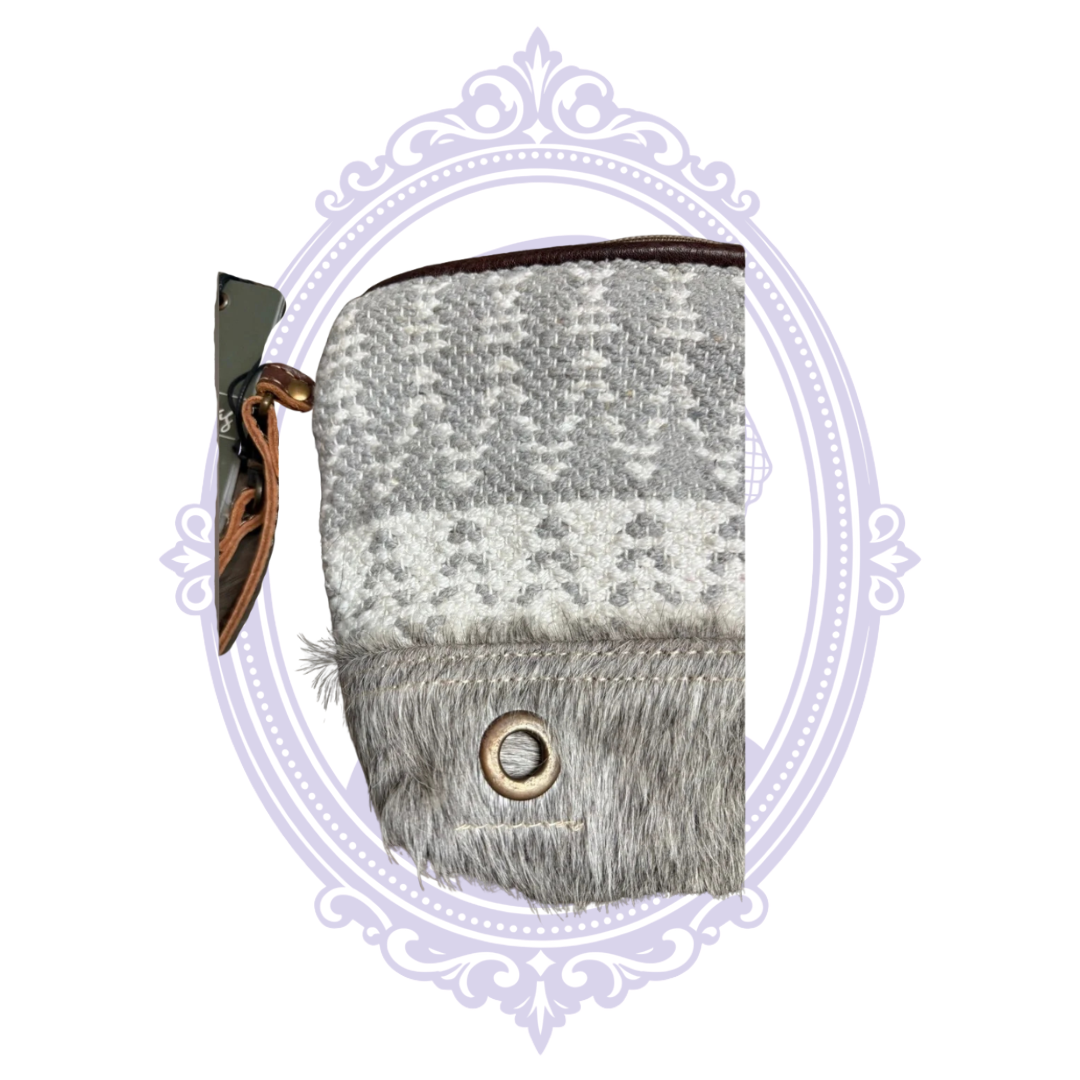 Close-up of the Myra Pasty Pouch featuring gray and cream Nordic-inspired woven fabric, gray hair-on-hide trim, and brass-tone grommet.
