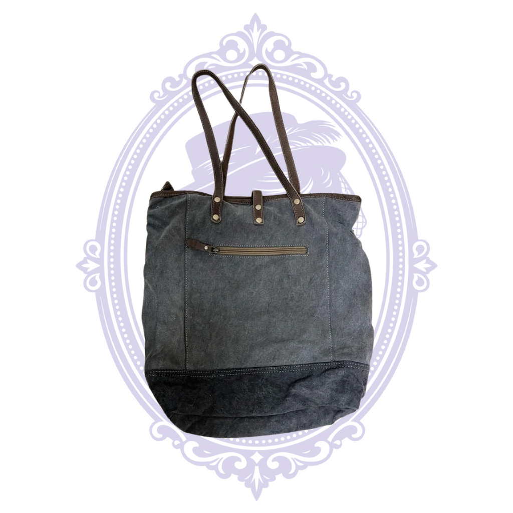 Close-up of geometric fabric and brown and gray base of Myra tote showing pre-owned condition.