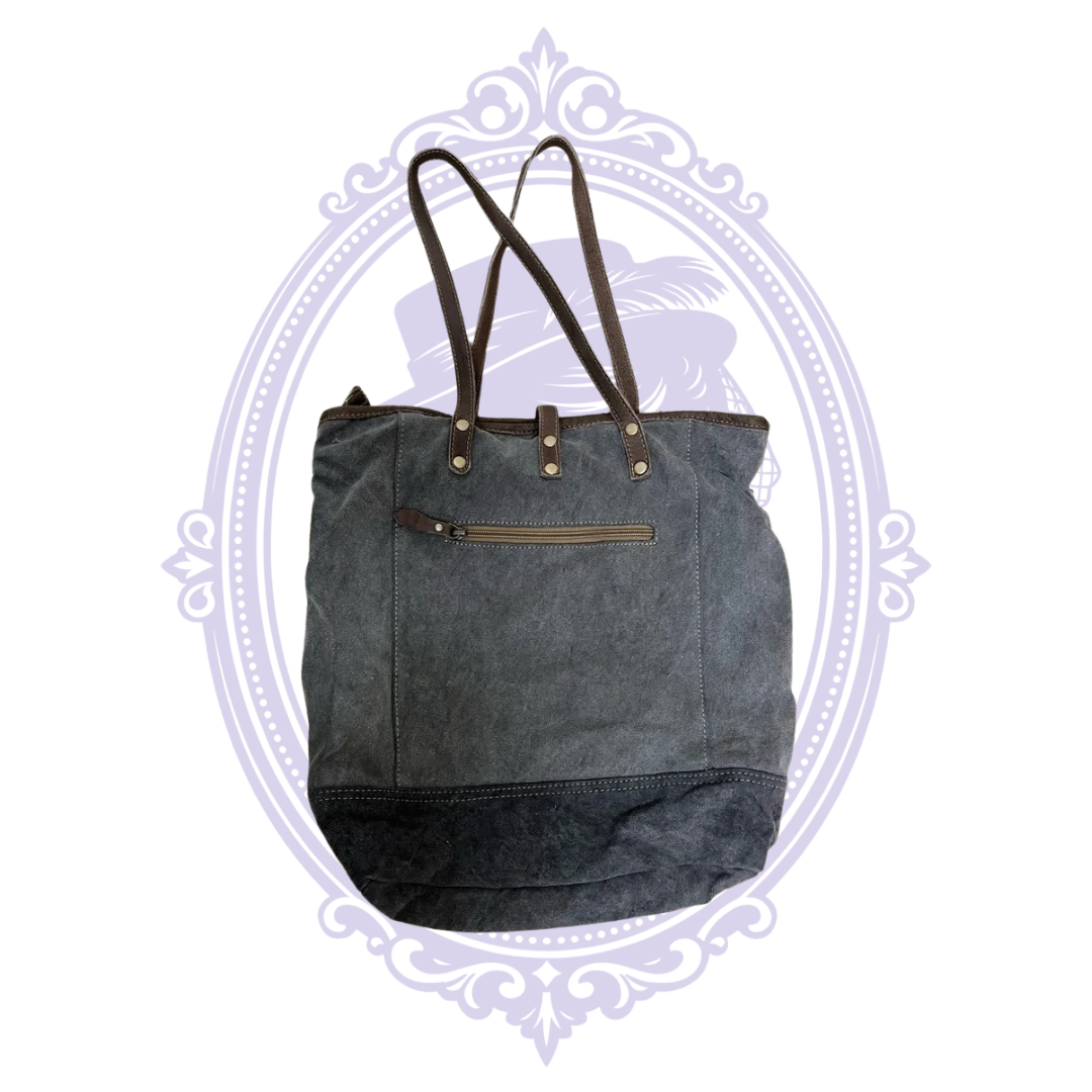 Close-up of geometric fabric and brown and gray base of Myra tote showing pre-owned condition.