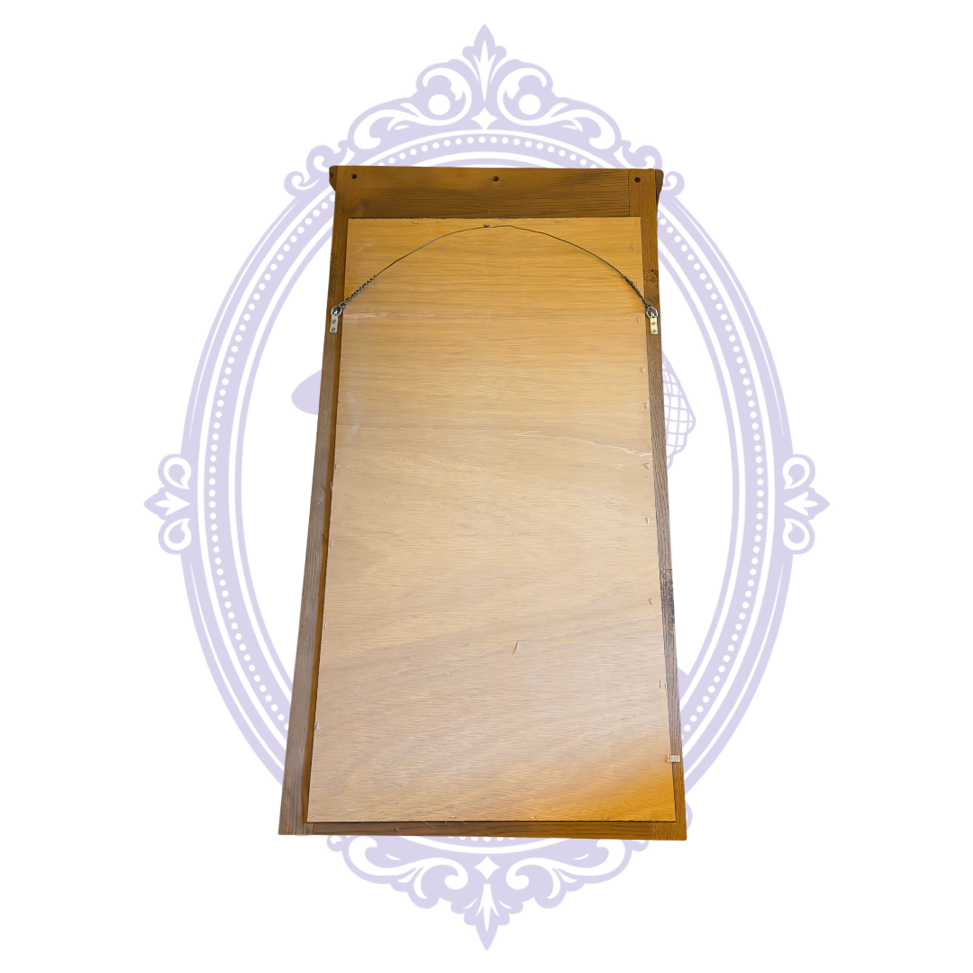 Back of rectangular wood framed mirror showing hanging wire on lavender decorative backdrop