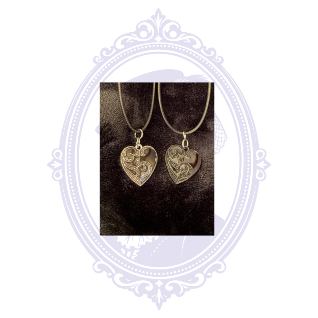 Side-by-side comparison of black and silver detailed ornate heart pendant necklaces.