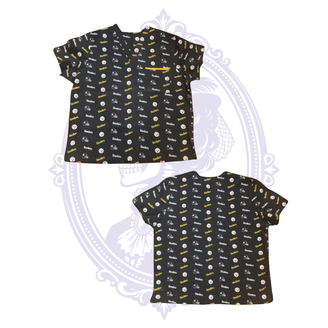 Front and back views of black Pittsburgh Steelers women’s scrub top with all-over team logos, helmets and black and gold print.