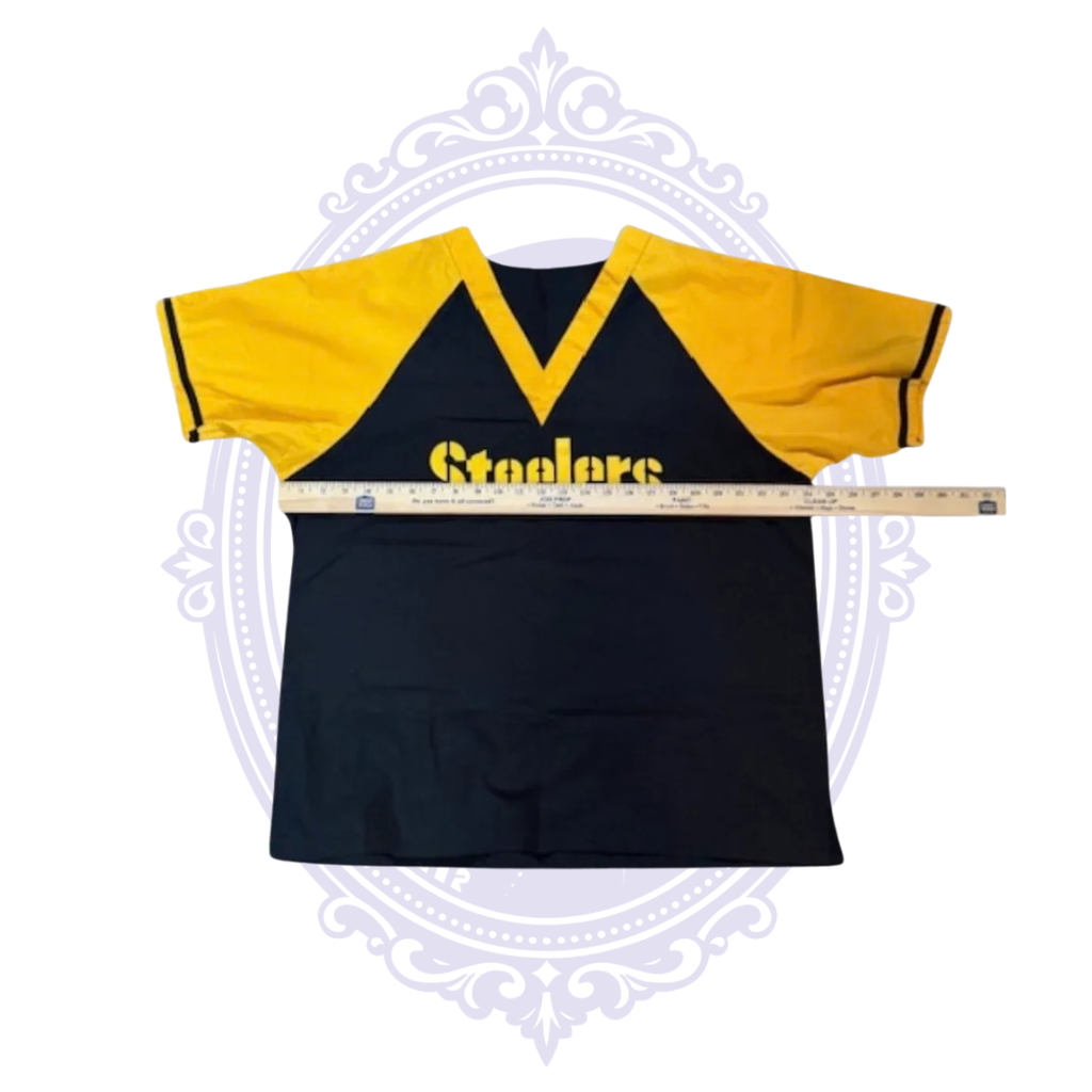 Pittsburgh Steelers black and gold scrub top laid flat with ruler across the chest for width measurement.