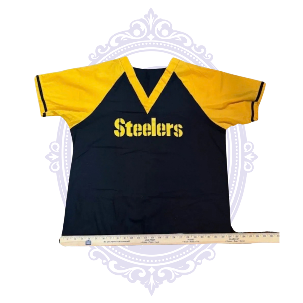 Pittsburgh Steelers black and gold scrub top laid flat with ruler across the bottom hem for width measurement.