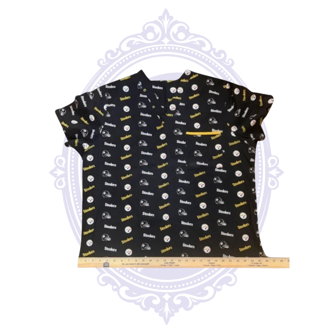 Pittsburgh Steelers black NFL logo print scrub top shown flat with ruler across the bottom hem for width measurement.