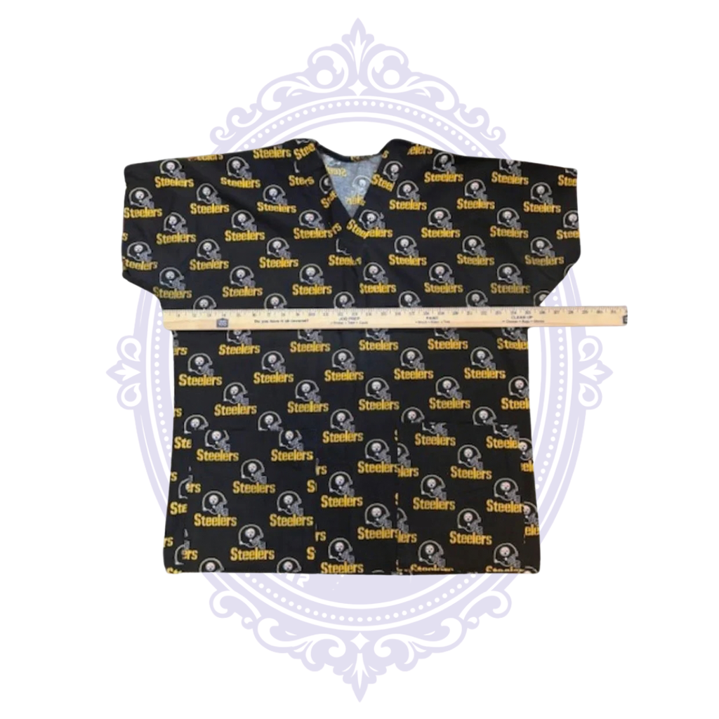 Pittsburgh Steelers helmet print scrub top laid flat with ruler across the chest for width measurement.