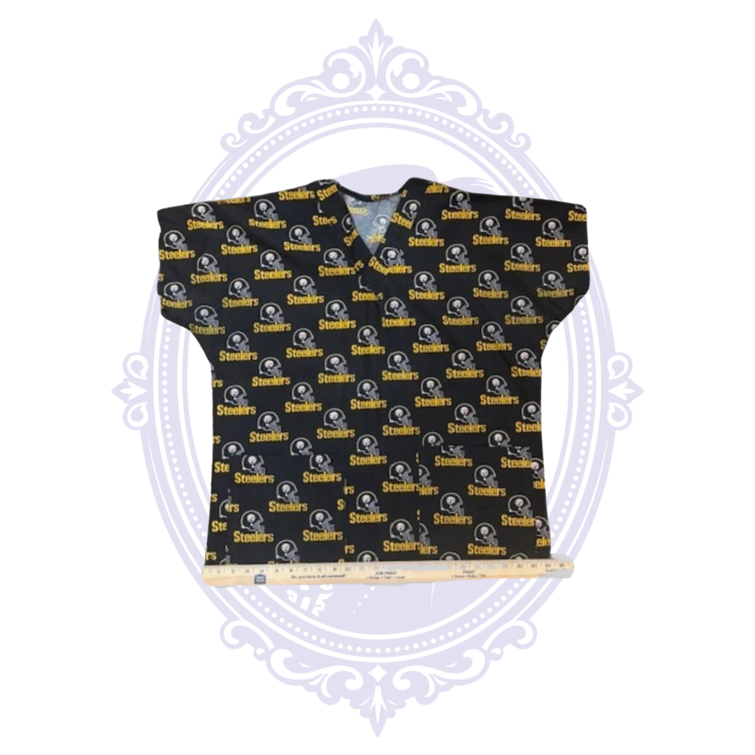 Pittsburgh Steelers helmet print scrub top laid flat with ruler across the bottom hem for width measurement.
