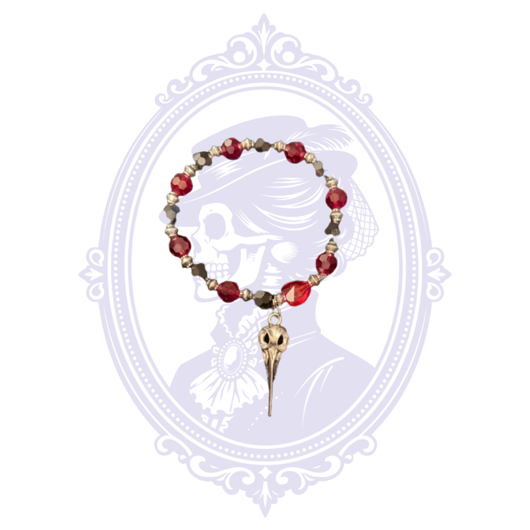 Cupboard Crafted bracelet with red faceted glass beads, metallic accents and elongated bird skull charm.