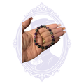 Purple and black glass bead stretch bracelet with silver-tone spacer beads shown in hand.
