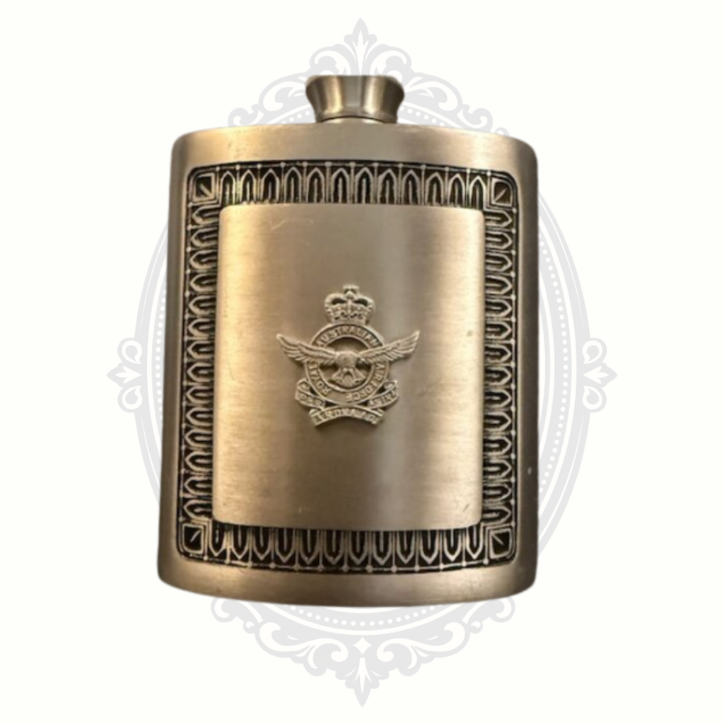 Vintage brass hip flask featuring a raised aviation emblem with wings and crown, framed by an ornate geometric border design