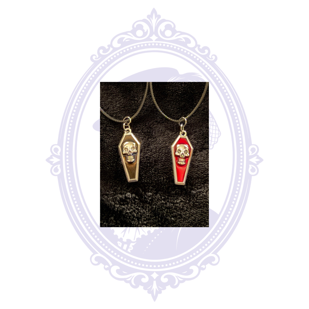 Red and black coffin pendant necklaces with raised silver-tone skull designs on black cords.