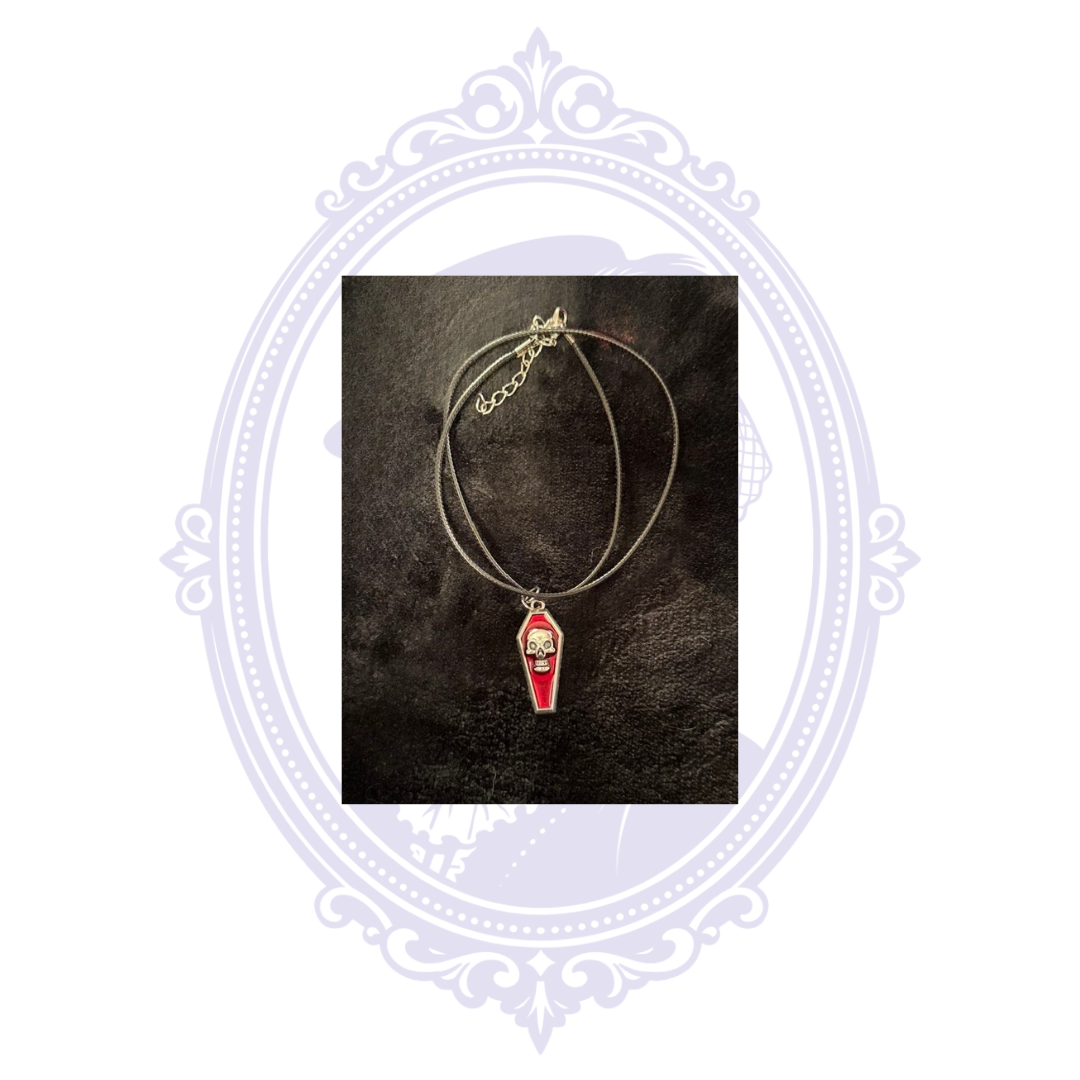 Red coffin pendant with raised silver-tone skull on an adjustable black cord necklace.