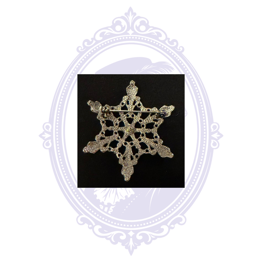 Back of silver-tone rhinestone snowflake brooch showing openwork construction and pin clasp.