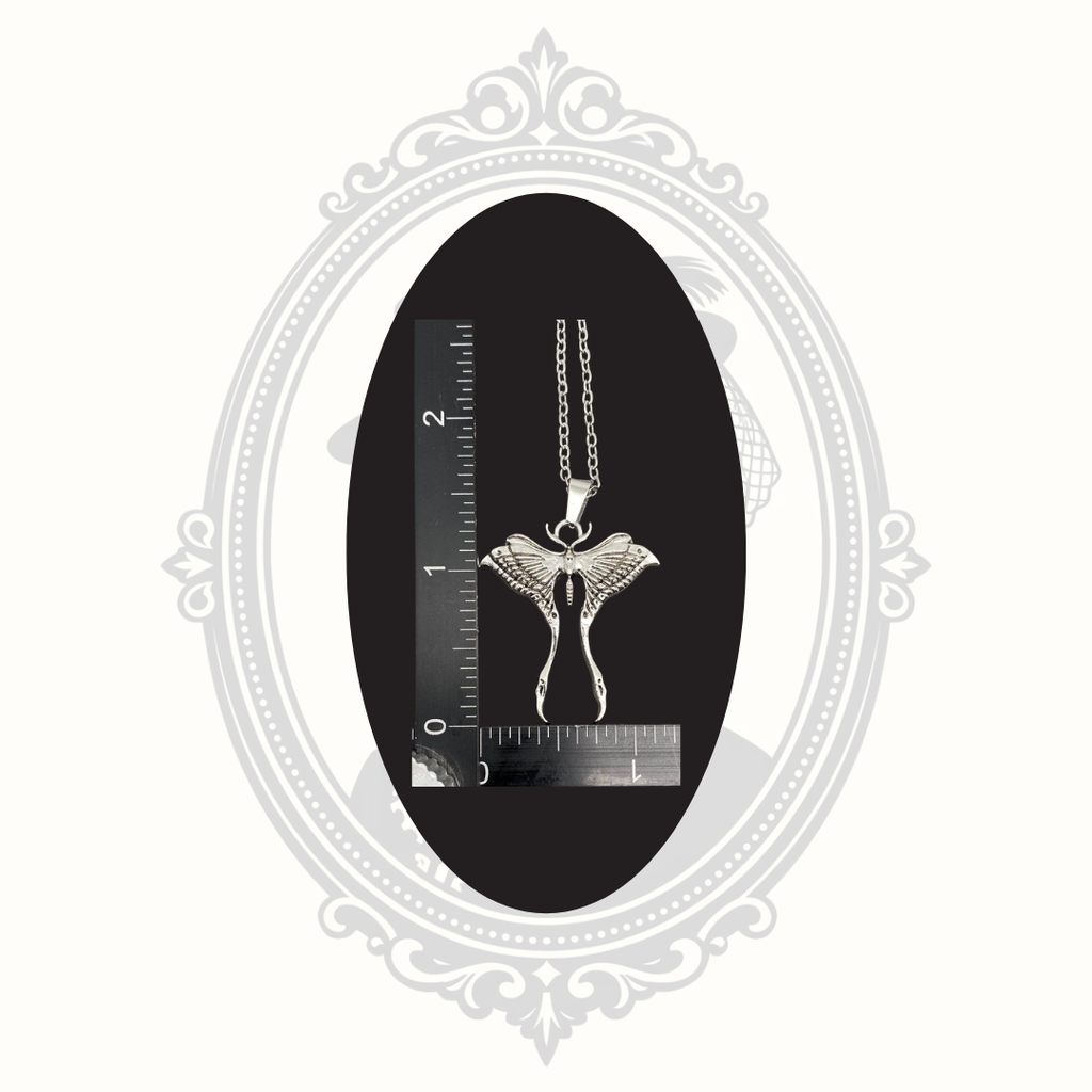 Silver-tone Luna moth pendant necklace shown beside a ruler for size reference.