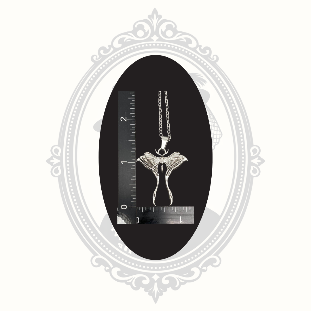 Silver-tone Luna moth pendant necklace shown beside a ruler for size reference.