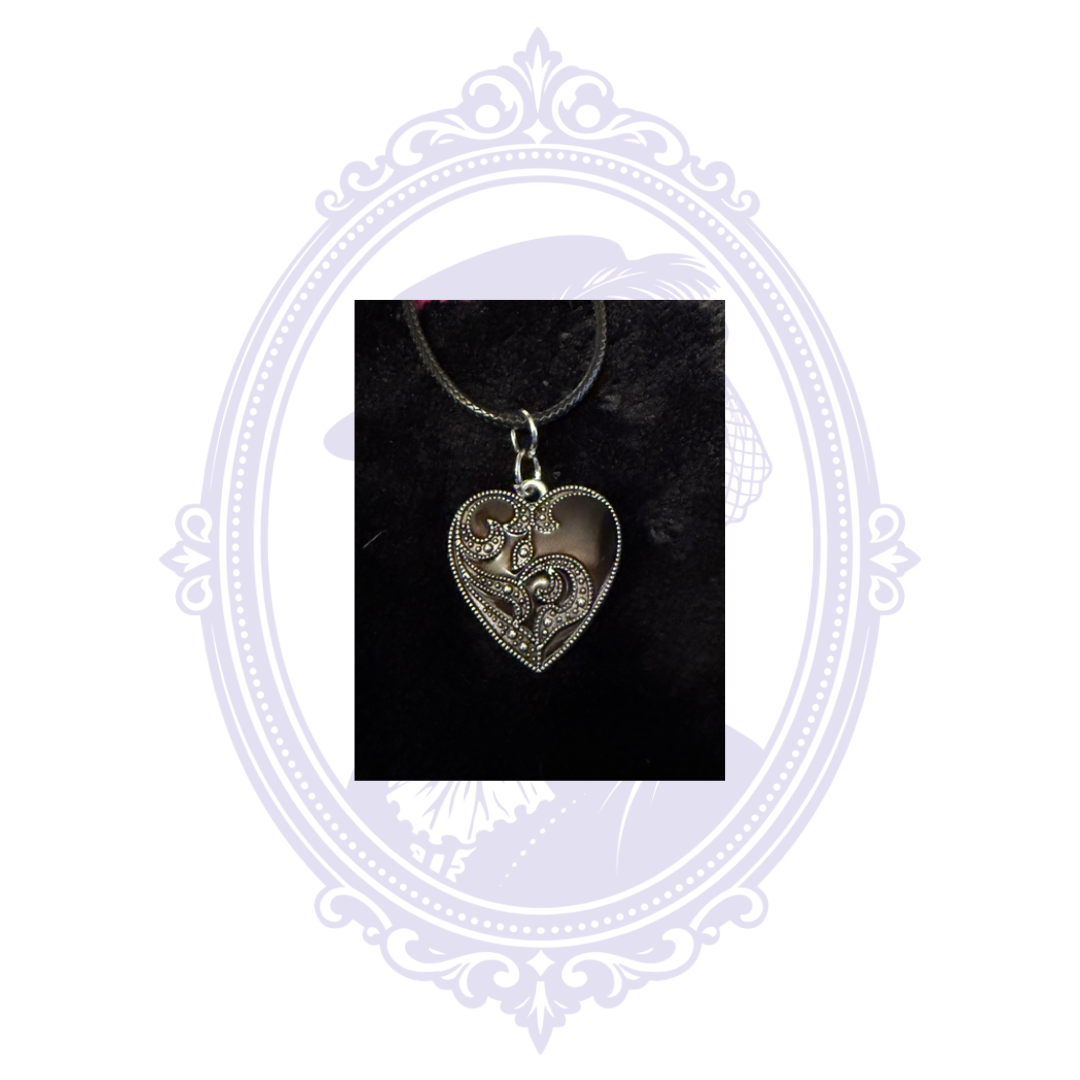 Silver-on-black ornate heart pendant with contrasting raised scrollwork and decorative details.