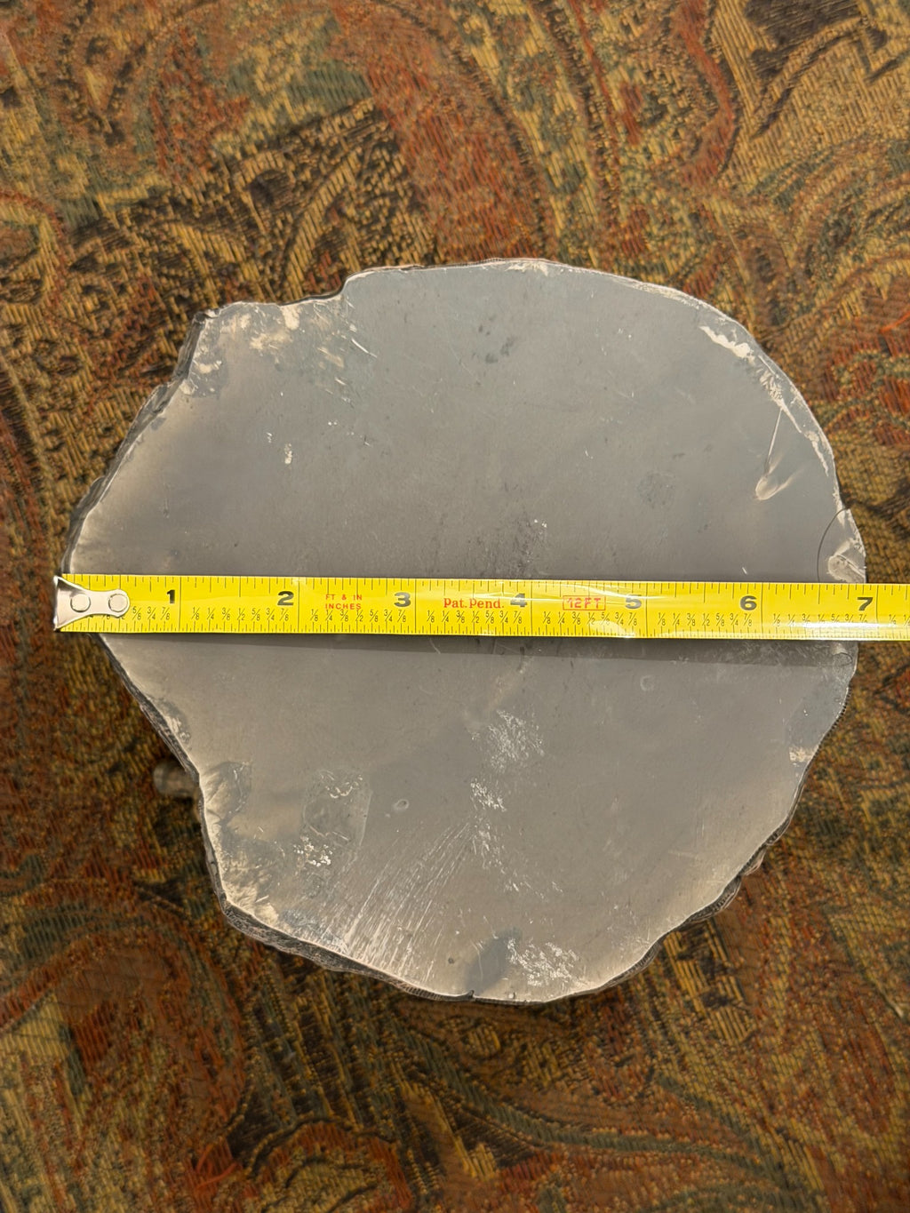 Underside of elephant candle holder beside ruler