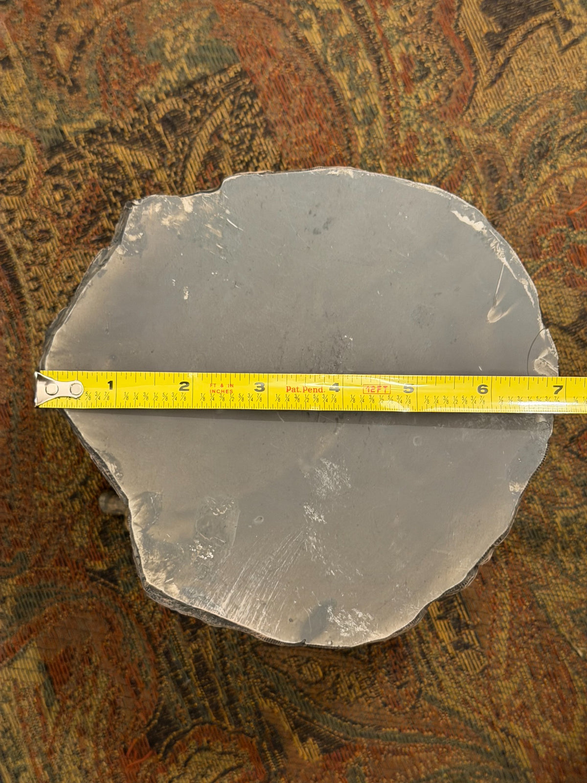 Underside of elephant candle holder beside ruler