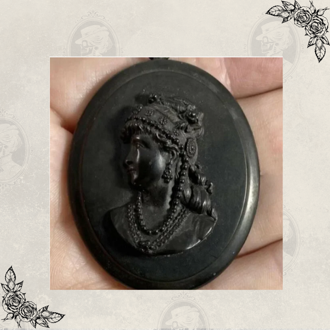 Antique Victorian mourning cameo pendant shown in hand for scale with detailed female portrait carving