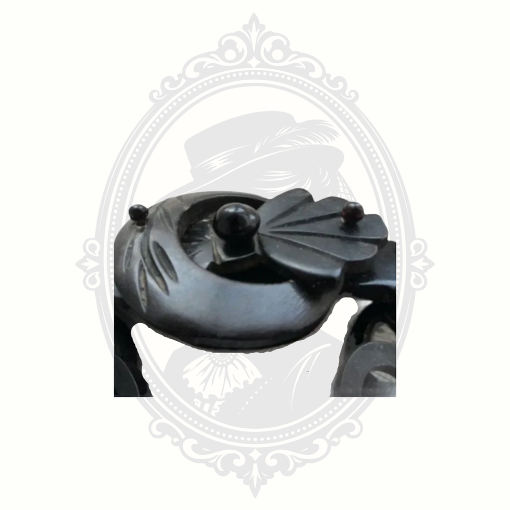 Close-up detail of Victorian gutta percha mourning brooch showing carved buckle and glass accent, mid to late 1800s