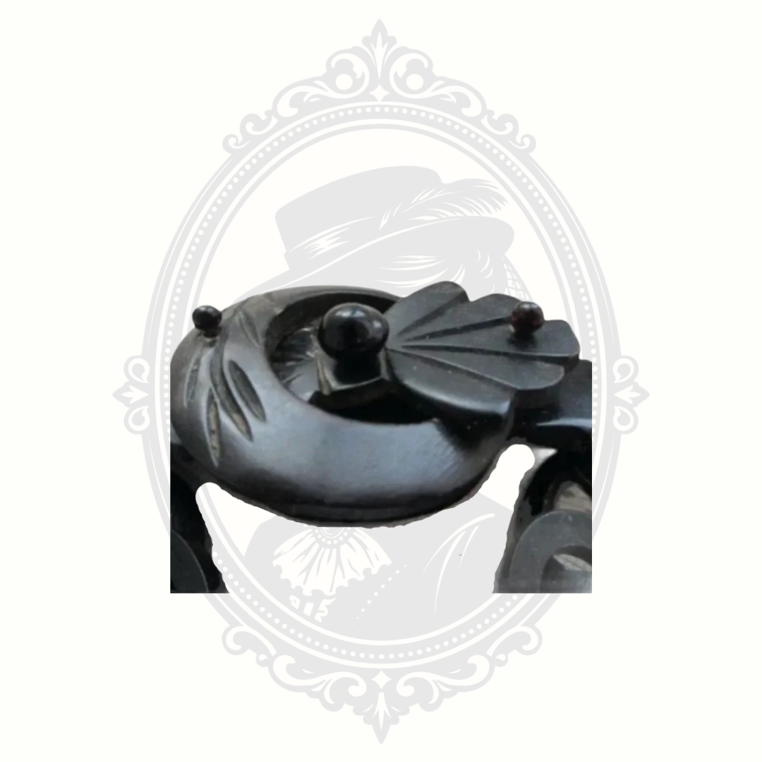 Close-up detail of Victorian gutta percha mourning brooch showing carved buckle and glass accent, mid to late 1800s