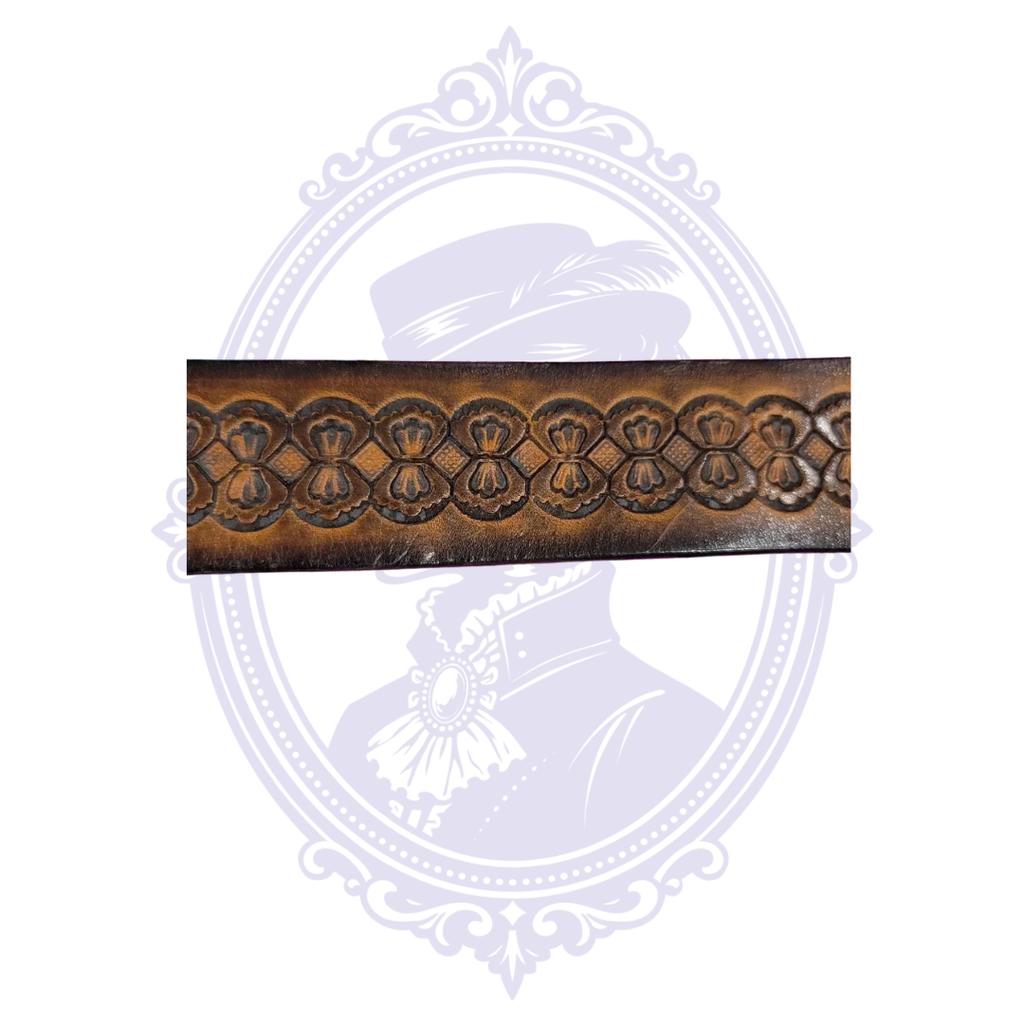 Close-up of brown leather belt showing a repeating row of bow-tie-like tooled motifs and small diamond accents.