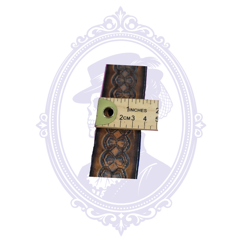 Brown tooled leather belt shown beside a measuring tape indicating approximately one and a half inches in width.
