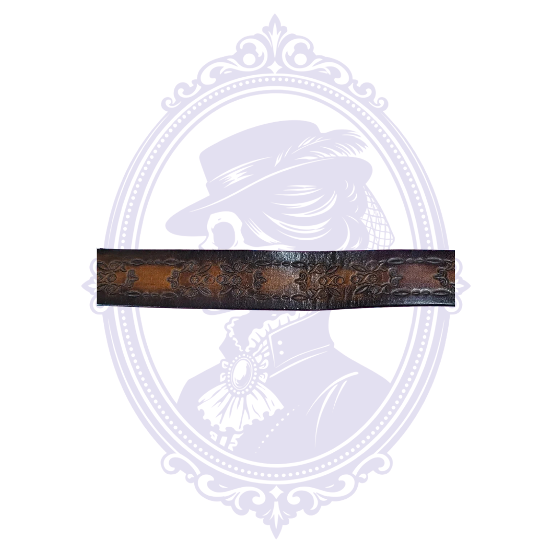 Flat detail of brown leather belt with repeating rectangular panels bordered by floral leaves and scrollwork.