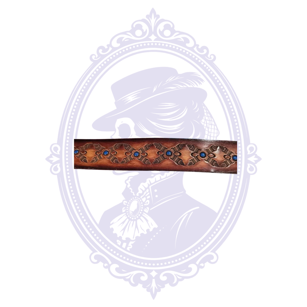 Close-up of repeating diamond-shaped geometric tooling with small round blue accents on a brown leather belt.