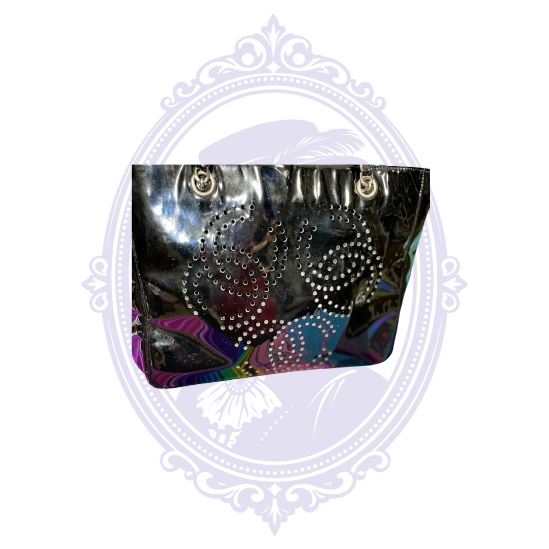 Close-up of perforated interlocking CC motifs on vintage Chanel Triple Coco black patent leather tote.