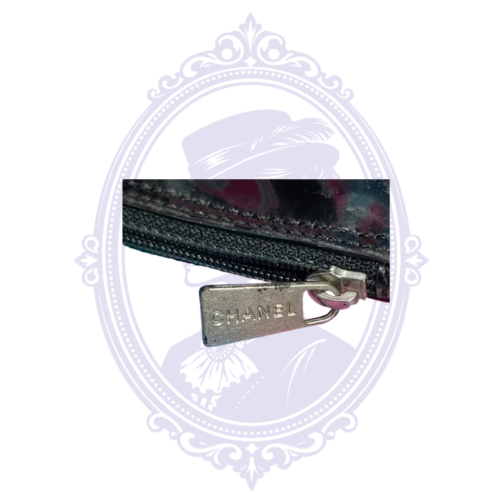 Close-up of Chanel engraved zipper pull on matching black patent leather pouch.